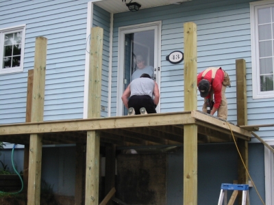 Shot of deck boards being applied with homeowner watching